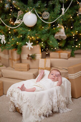 Fototapeta na wymiar Portrait of newborn baby boy lying under blanket next to gift boxes