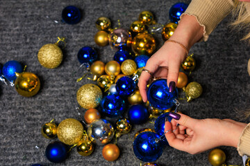 Christmas balls in female hands in the process of decorating the Christmas tree. Preparation for the holidays