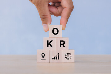 Business target and drive business and performance. Focus on goal. Achieve business growth by flexible management. OKR text (Objectives, Key and Results) wooden cube blocks on blue background.