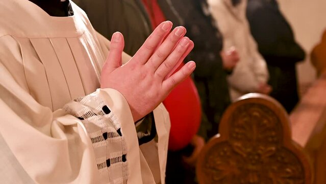 Catholic priests praying with hands folded. Hands of Christian man praying in Cathedral. Christmas Midnight Mass in church.  