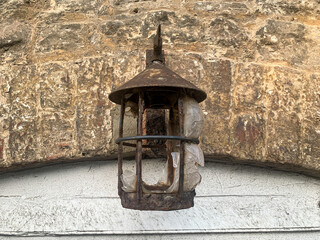 Cracked kerosine lantern on the old brick wall above the door. Old lantern hanging on the wall.