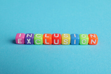 Colorful cubes with word Inclusion on light blue background, above view
