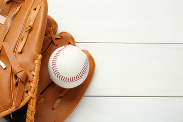 Leather baseball glove with ball on white wooden table, top view. Space for text