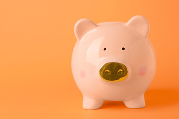 Ceramic piggy bank on orange background. Space for text