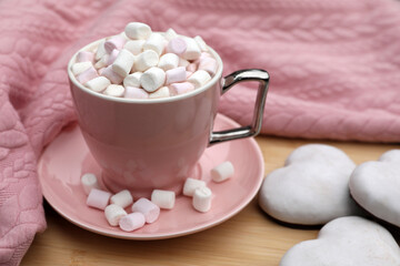 Fototapeta na wymiar Cup of tasty cocoa with marshmallows, pink sweater and cookies on wooden table