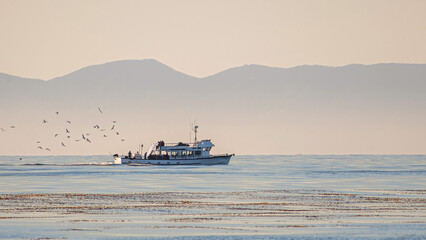 Obraz premium Sailing boat in Pacific ocean against the backdrop of mountains