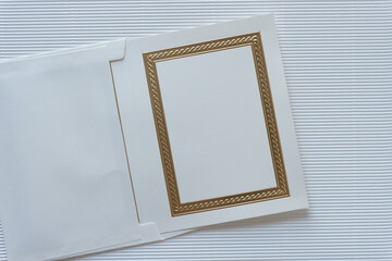 elegant gold foil embossed invitation card partly tucked inside an envelope and arranged on...