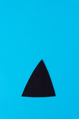 Fototapeta premium black paper triangle with rounded edges on smooth blue paper