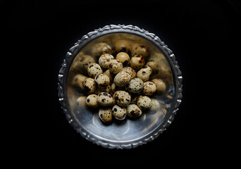 quail eggs in a metal basket on a black background