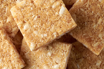close-up macro view of coconut biscuits, textured crispy square shaped homemade cookies in full frame, food background