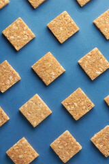 coconut biscuits pattern, crispy square shaped homemade cookies on textured blue surface, flat lay food background