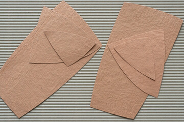two piles of cut paper shapes on corrugated paper
