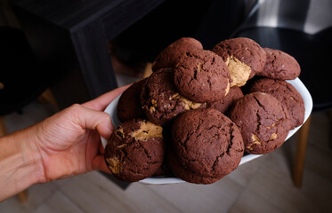 Woman's hand showing a fluffy thick chocolate brownie cookie cut in half with peanut 