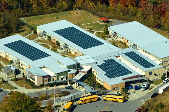 Aerial view of american school building with rooftop covered with photovoltaic solar panels for production of electric energy