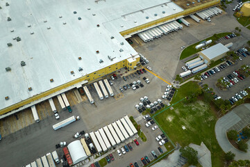 High angle view of big commercial shipping center with many freight trucks unloading and uploading...