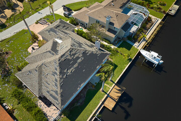 Wind damaged house roof with missing asphalt shingles after hurricane Ian in Florida. Repair of...