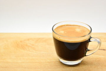 glass of black coffee put on wooden cutting board