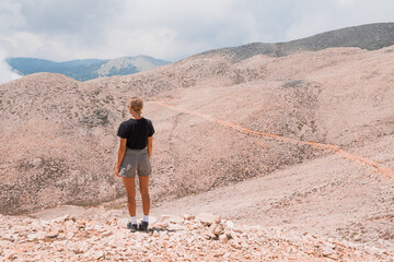 Fototapeta premium The girl stands on the edge of a high mountain in the clouds. The girl looks at the beautiful mountain landscape Antalya Turkey