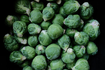 Fototapeta na wymiar Lots of green brussels sprouts in the air small brussels sprouts on black background A whole page of Brussels sprouts background texture