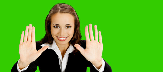 Portrait of happy smiling young business woman in black suit showing stop gesture. Cheerful busiesswoman showing holding raising open hands, palms. Green chroma key background.