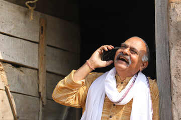 old Indian farmer talking on mobile phone at home