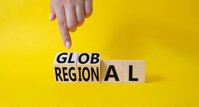 Global and Regional symbol. Businessman hand points at turned wooden cubes with words Regional and Global. Beautiful yellow background. Business and Global and Regional concept. Copy space