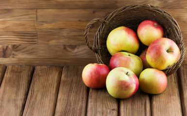 Close-up view of red apples spill out of the basket on wooden background
