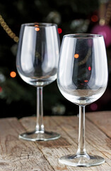 Empty wine glasses with festive lights on a wooden table.