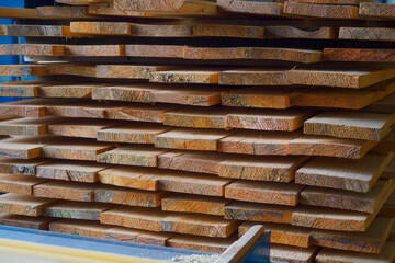 Wooden boards are stacked in a sawmill or carpentry shop. Sawing drying and marketing of wood. Industrial background.