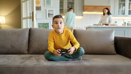 Boy kid playing video computer game at home living room