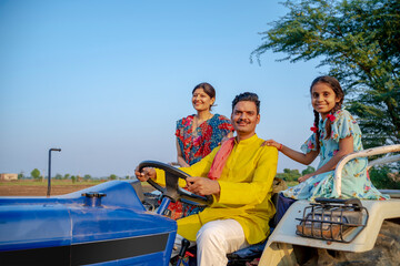 Indian farmer sitting on tractor with wife and little daughter. Indian rural family.
