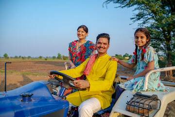 Indian farmer sitting on tractor with wife and little daughter. Indian rural family. - obrazy, fototapety, plakaty