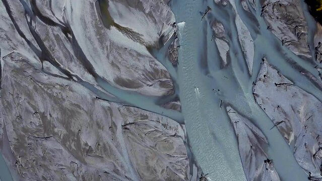 Turquoise glacial water, filled with minerals, braids through the sandy riverbed of Knik River, Alaska