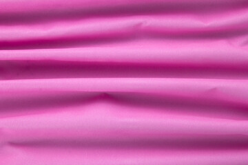 Beautiful wavy pink cotton, traditional cloth material textile on top view and close up.