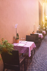 Street italian restaurant, small tables for two with pink tablecloth. Street cafe in Italy. Travel...