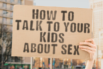The phrase " How to talk to your kids about sex " is on a banner in men's hands with blurred background. Erotic. Equality. Training. University. Safety. Protect. Organ. Adoption. Publicity. Gynecology