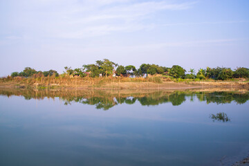Canal with trees and vegetation reflected in the water nearby Padma river in Bangladesh