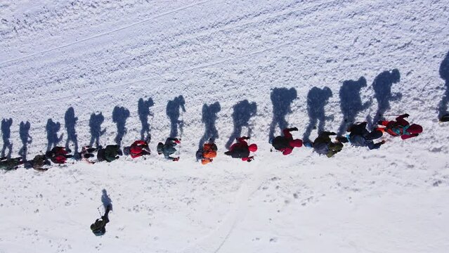 Top down view of a large group of climbers climbing up a snowy slope