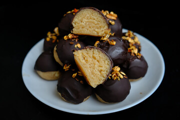 healthy protein candies in chocolate with peanuts and coconut on a black background