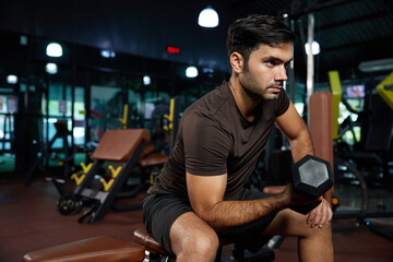 young sports man lifting dumbbell in the gym