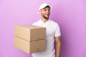 Delivery caucasian man isolated on purple background laughing