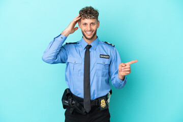 Young police blonde man isolated white on blue background surprised and pointing finger to the side