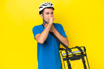 Young handsome man with thermal backpack over isolated yellow background is suffering with cough...