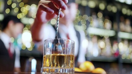 Asian man bartender preparing cocktail drink in cocktail glass serving to customer on counter at luxury restaurant bar. Barman making mixed alcoholic drink for celebrating holiday party at nightclub.