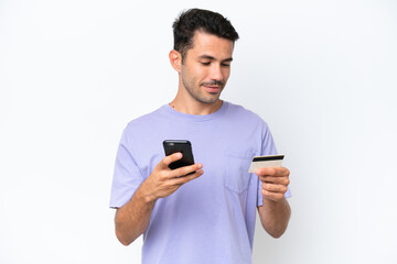 Young handsome man over isolated white background buying with the mobile with a credit card