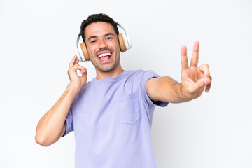 Fototapeta premium Young handsome man over isolated white background listening music and singing