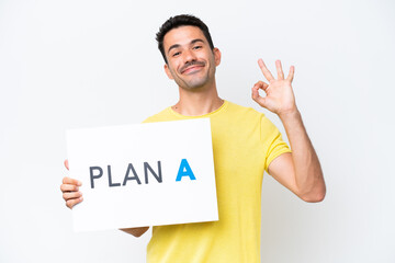 Young handsome man over isolated white background holding a placard with the message PLAN A with ok sign