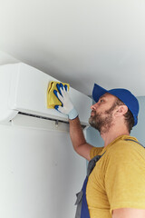 Repairman cleaning and fixing indoors AC unit.
