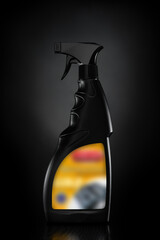 A black plastic bottle with a liquid spray on a black background designed to evenly distribute the liquid on the washing surface
