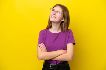 Young English woman isolated on yellow background looking up while smiling